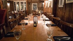 A long wooden dining table set with chairs, glasses, and a small lantern in the center. - Grafton Inn (Grafton)