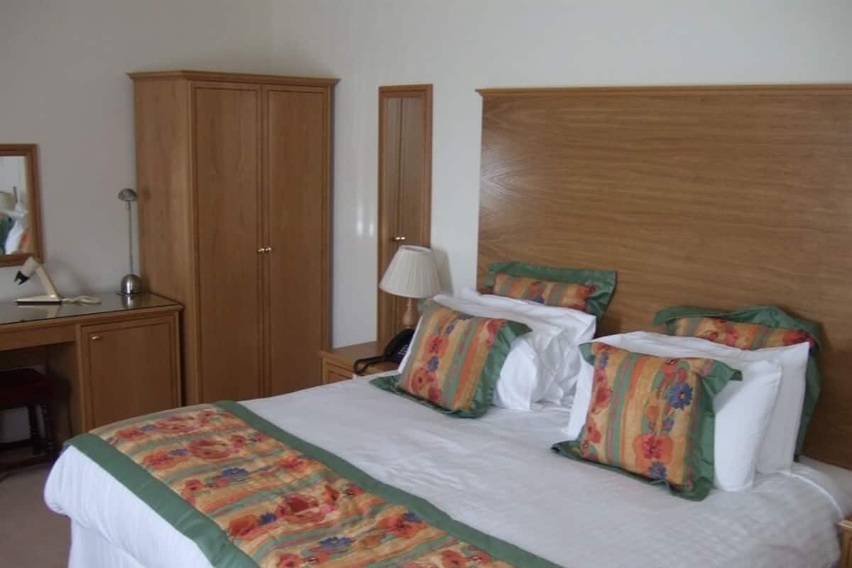 Quarto bem organizado com uma cama grande, uma escrivaninha e um guarda-roupa.