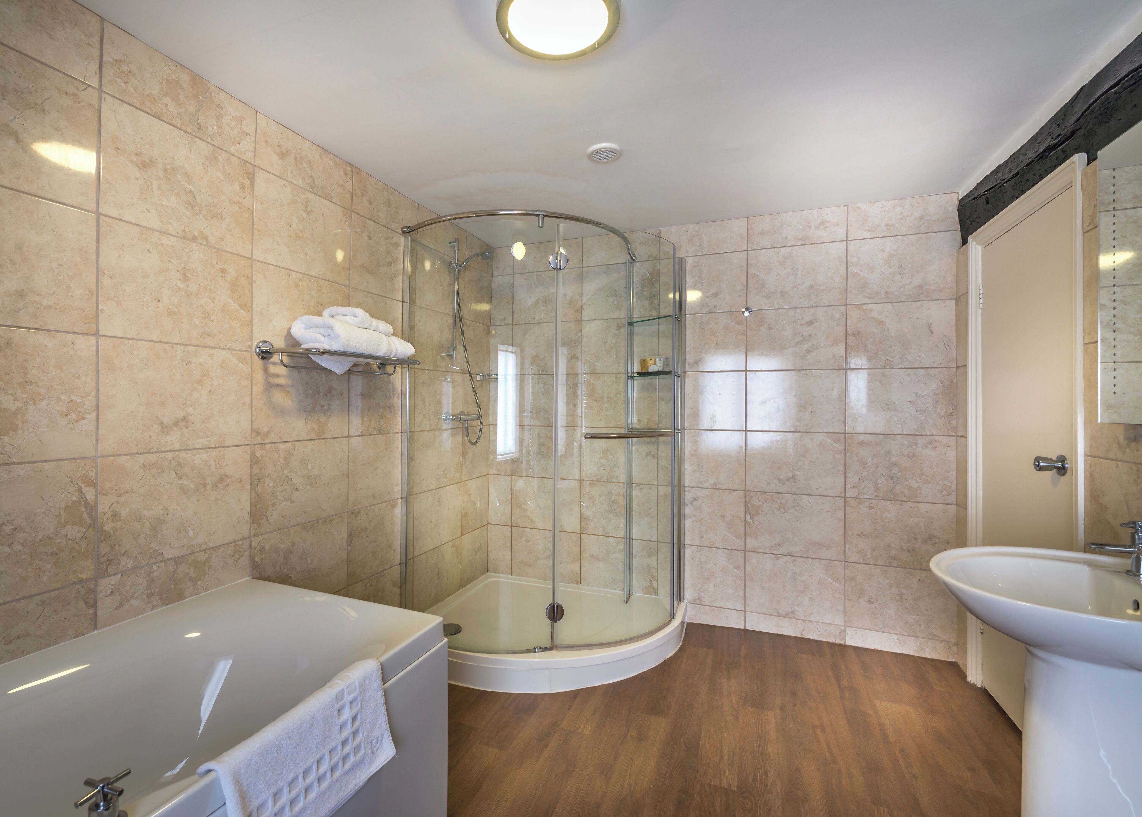 A modern bathroom with a glass-enclosed shower, a bathtub, and a sink.