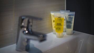A bathroom sink with three toiletry bottles labeled "H2K Harrogate" and "COACHING INN GROUP."