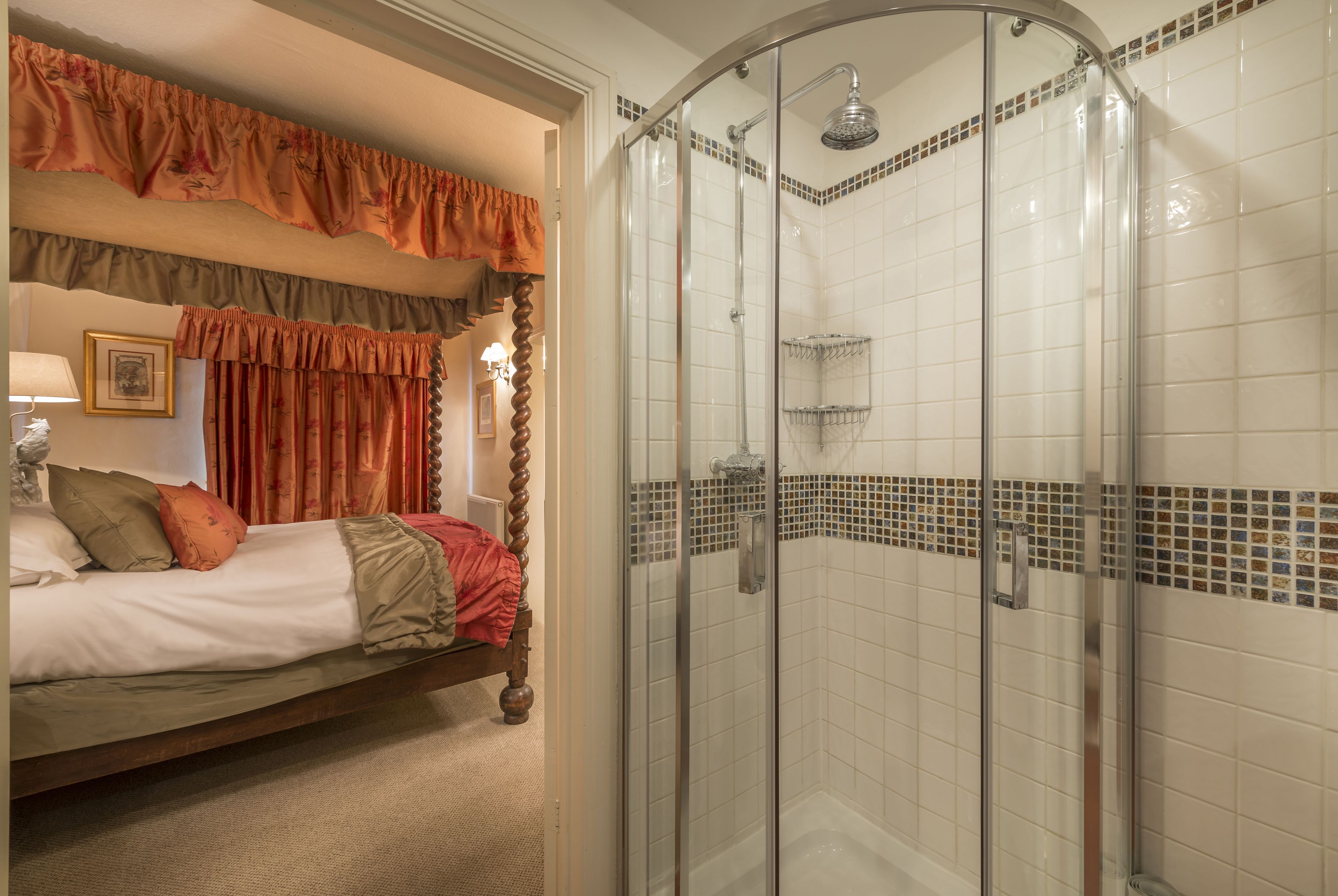 Quarto de hotel com uma cama, um chuveiro com porta de vidro e área do chuveiro azulejada.