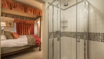Quarto de hotel com uma cama, um chuveiro com porta de vidro e área do chuveiro azulejada.