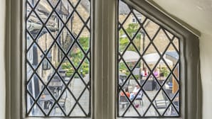 Une fenêtre ornée d’une grille à motifs losangés, qui fait partie de la façade d’un bâtiment.