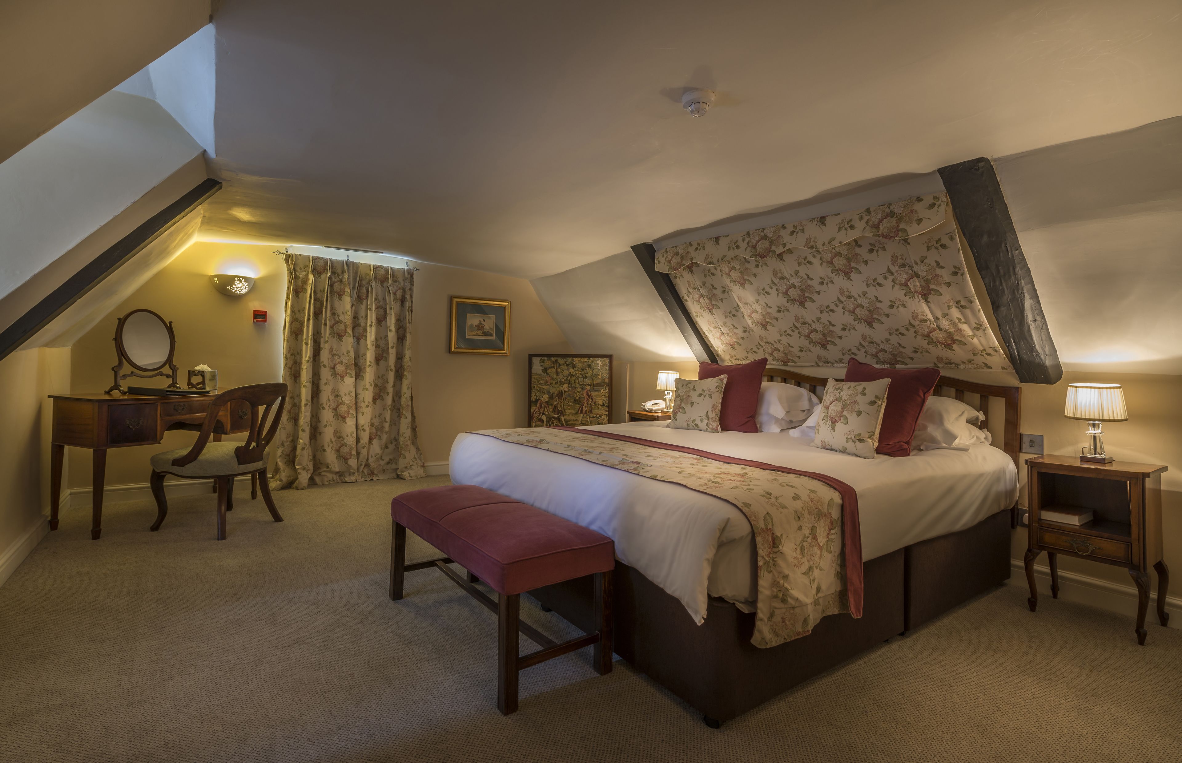 A bedroom with a large bed, a desk, a chair, and a bench.