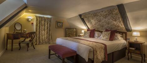 A bedroom with a large bed, a desk, a chair, and a bench.