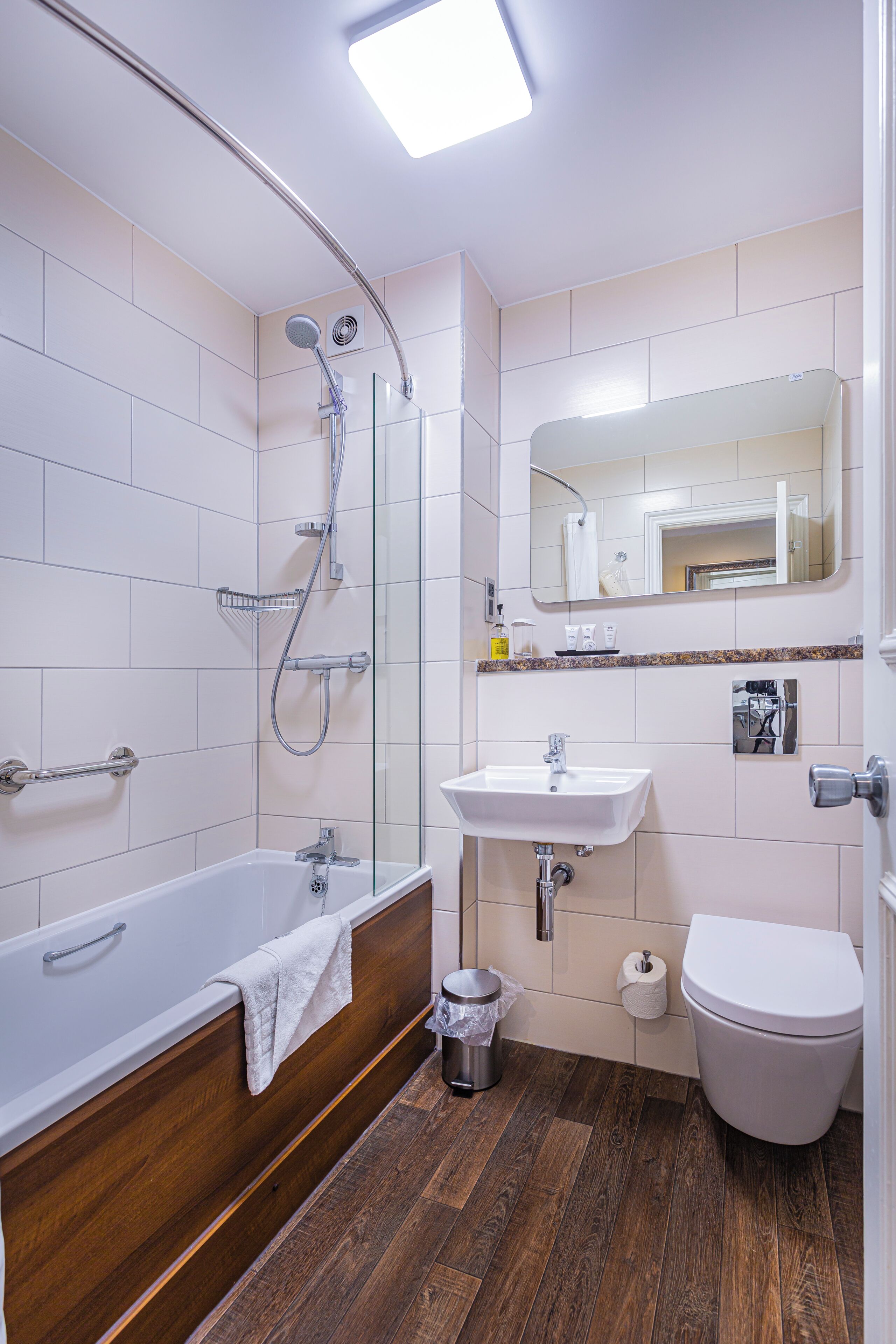 Un baño con bañera, ducha, lavabo, inodoro y espejo.