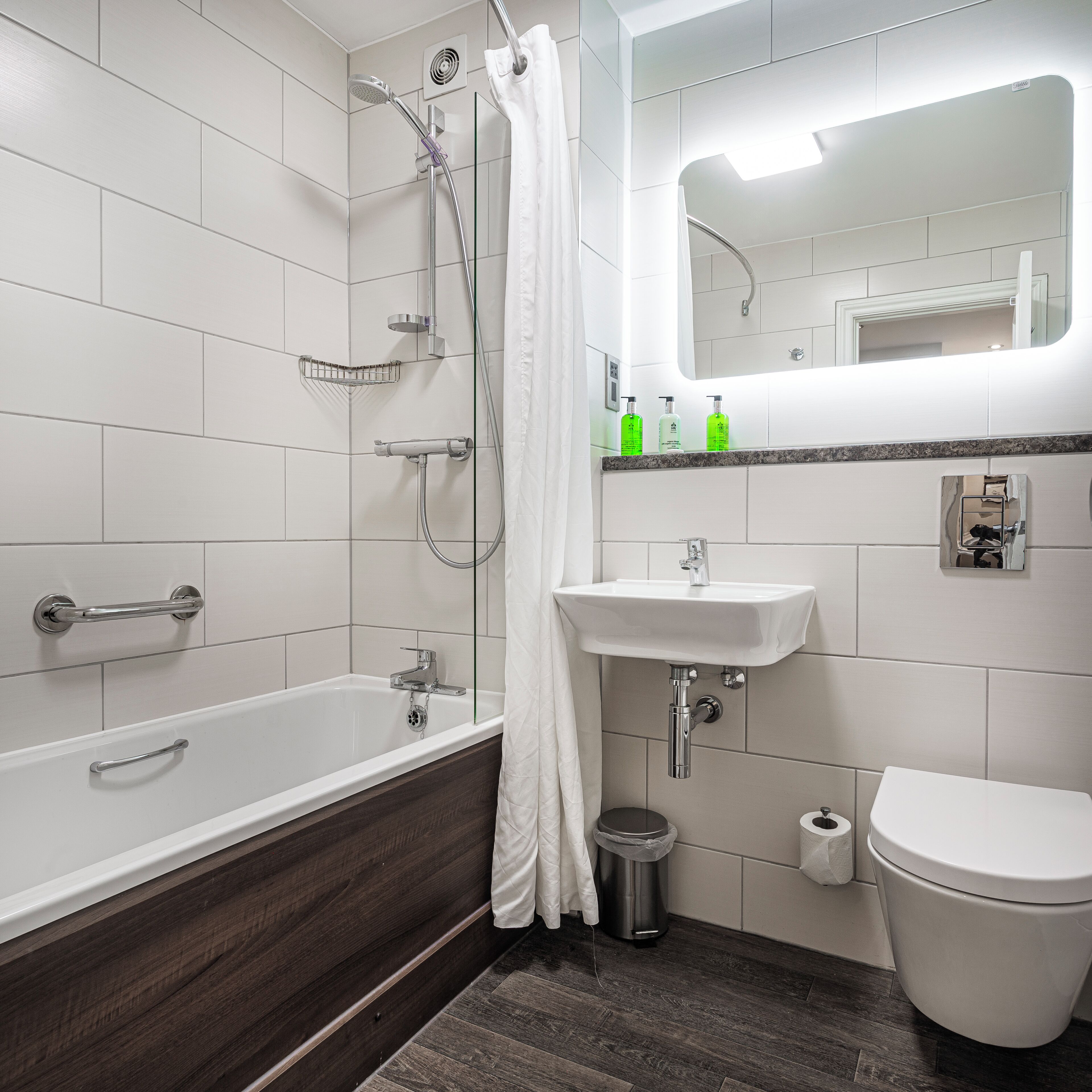 Et moderne badeværelse med badekar, bruser, vask og toilet.
