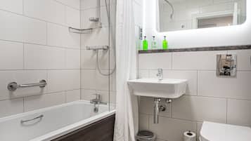 Et moderne badeværelse med badekar, bruser, vask og toilet.