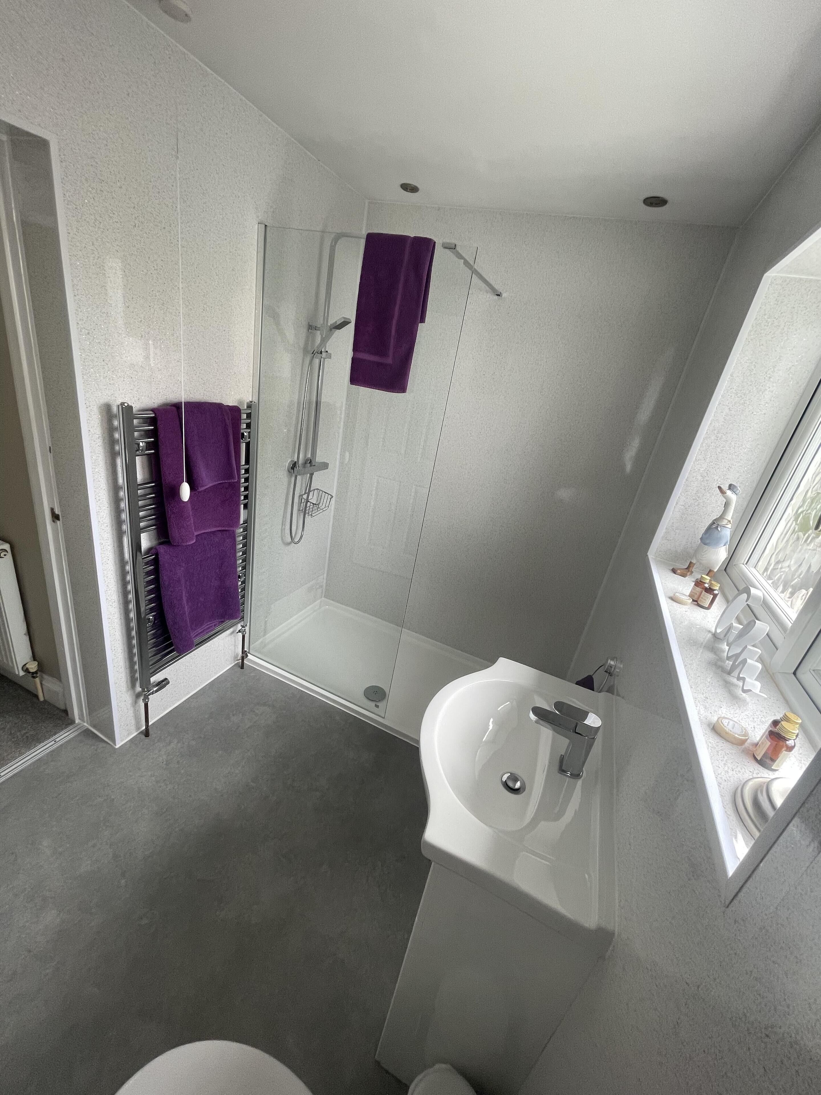 Un baño moderno con cabina de ducha de vidrio, lavamanos blanco y un espejo grande.