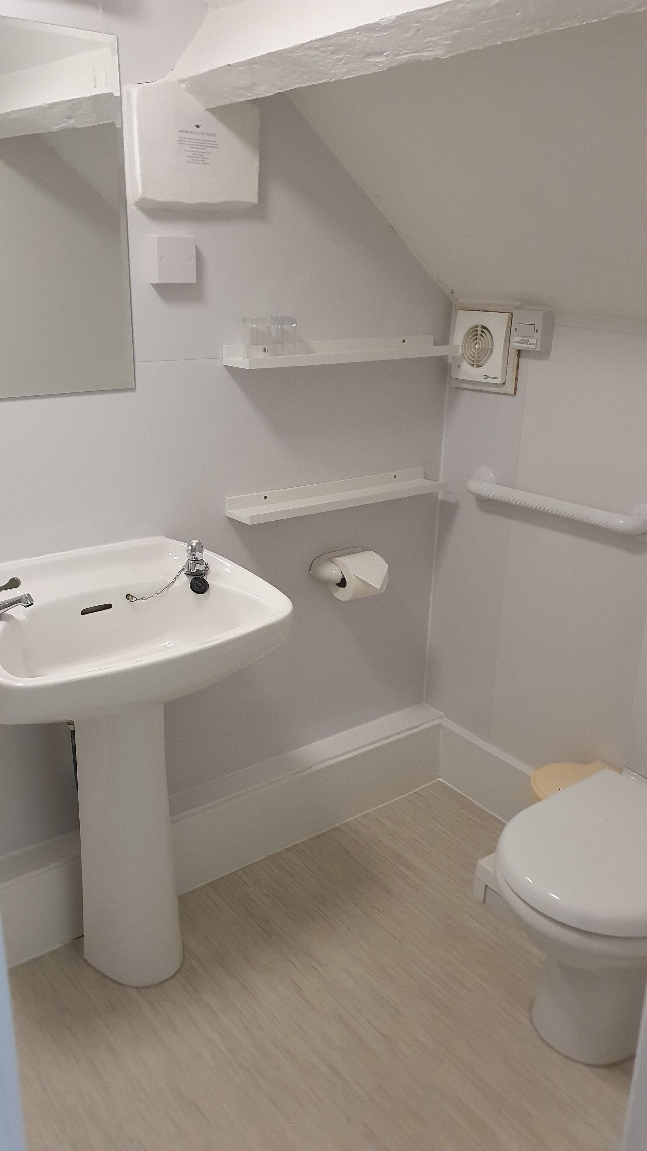 A bathroom with a white sink, toilet, and shelves.