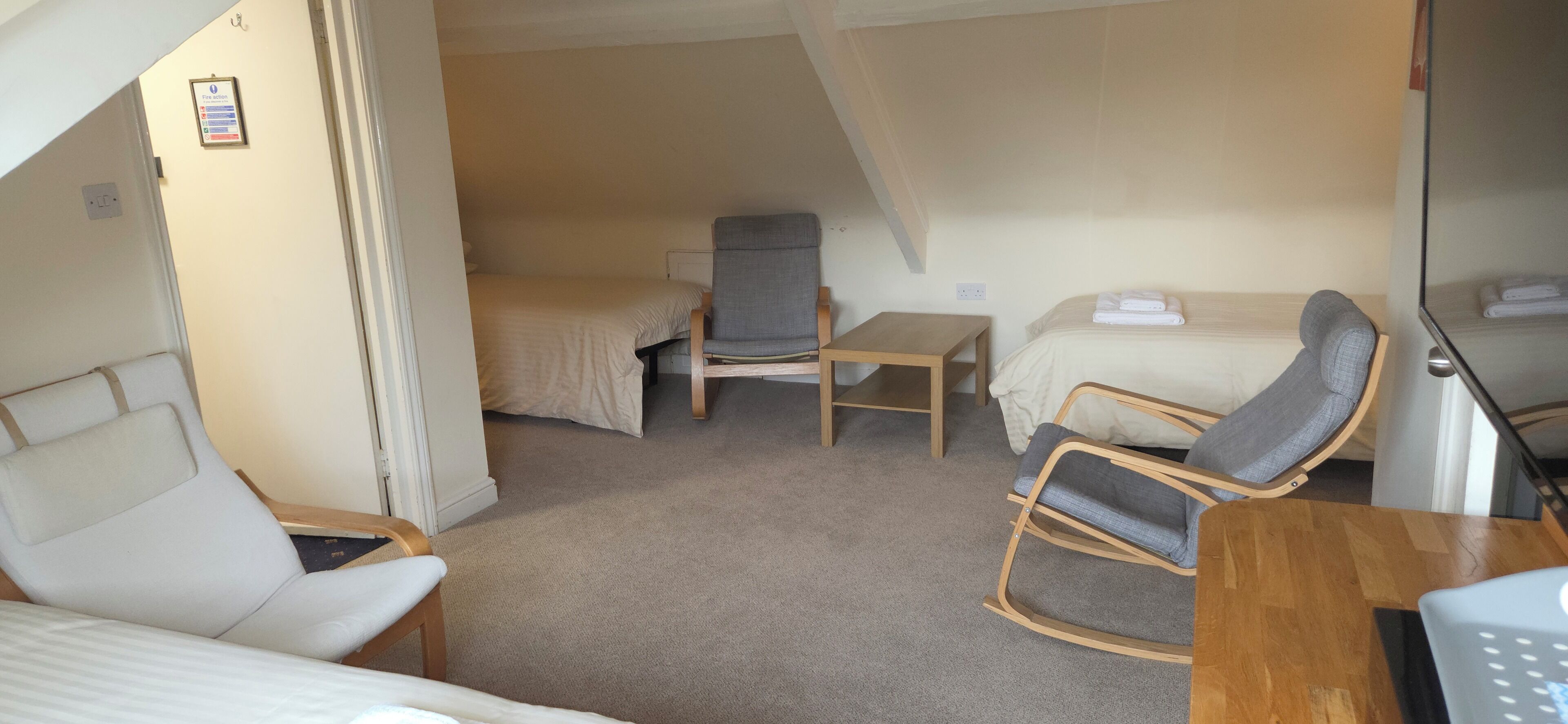 A compact room with a bunk bed, a single chair, a small table, and a bed with a pillow and blanket.