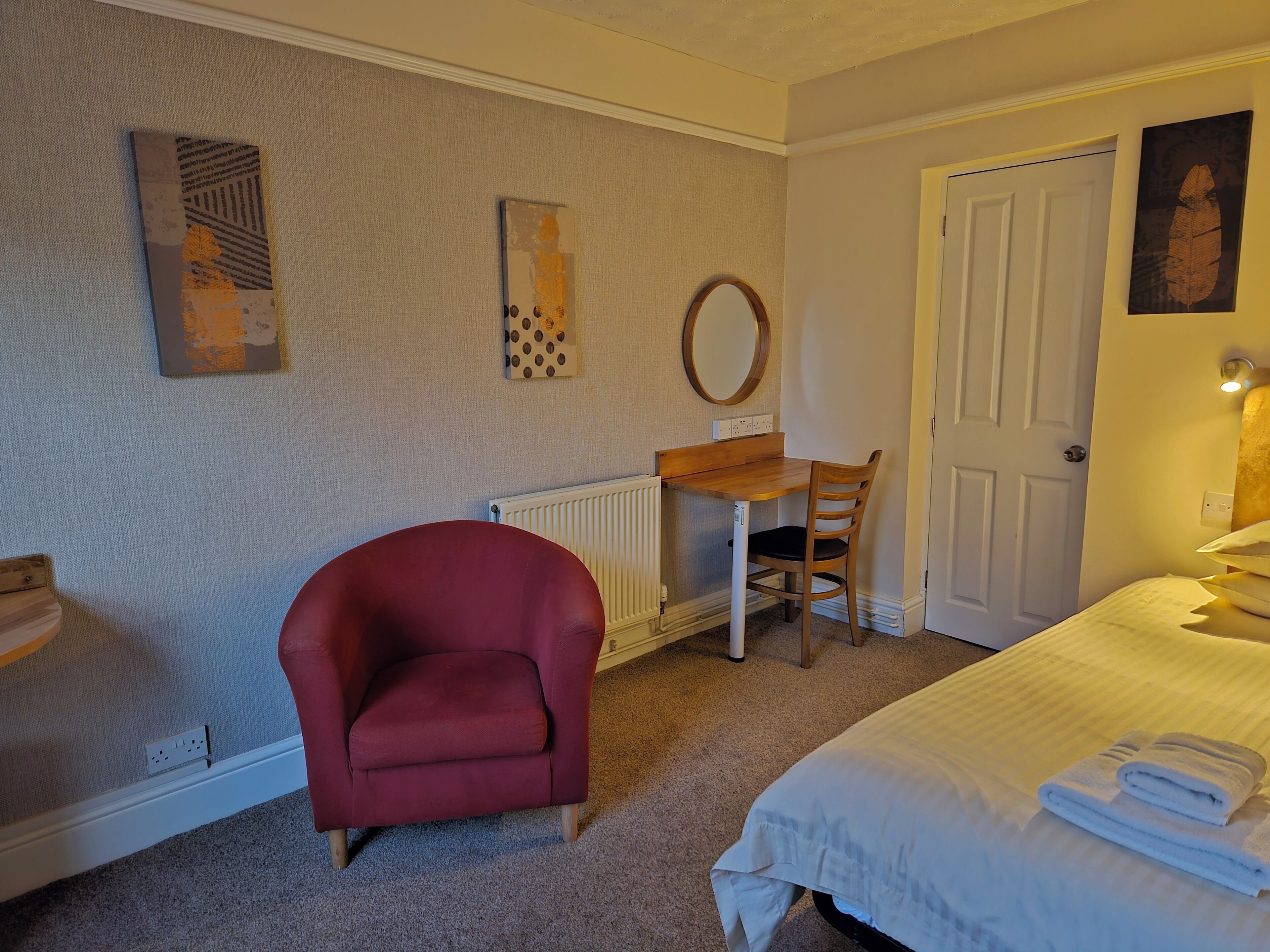 A bedroom with a bed, a desk, a chair, and a radiator.