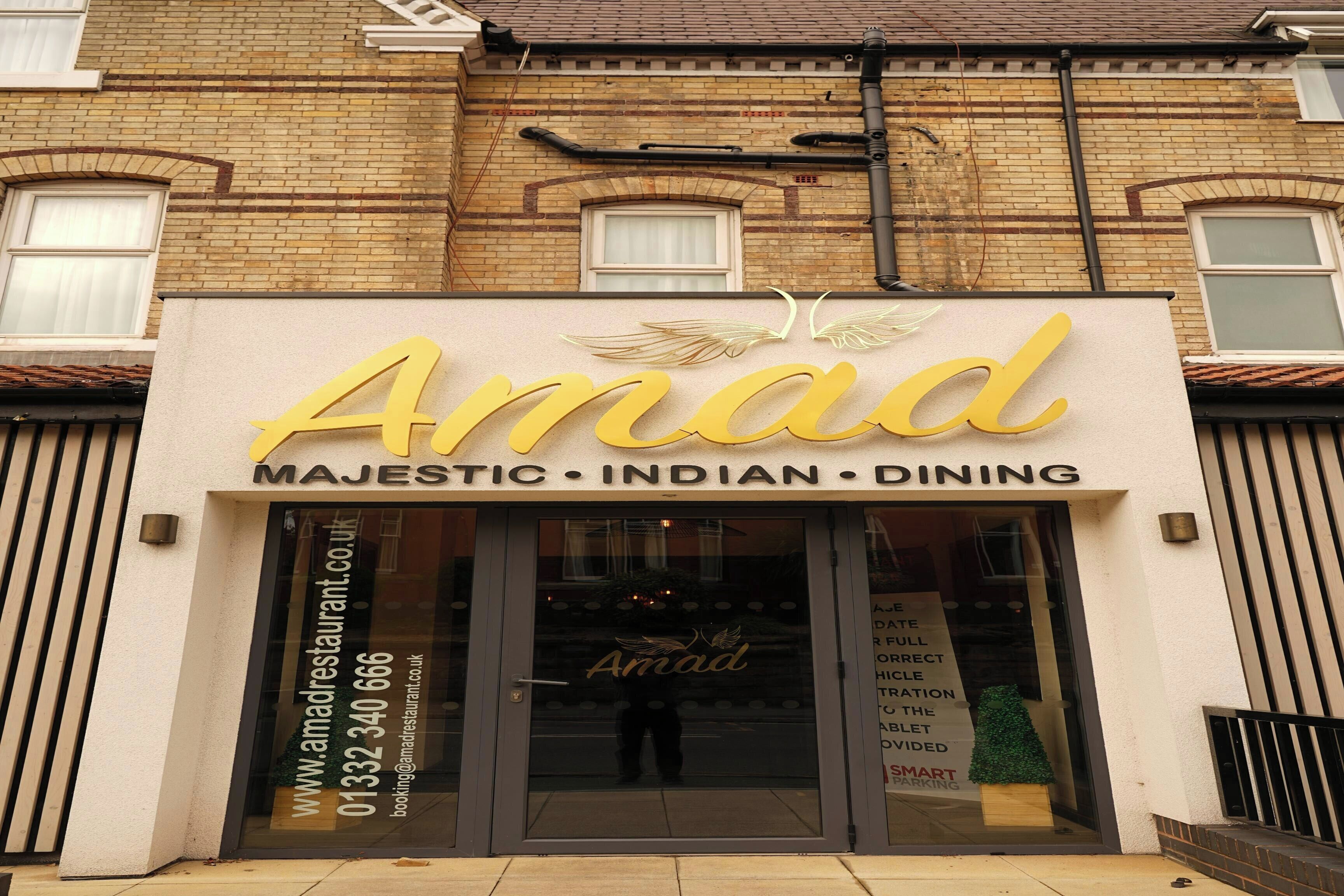 A building with a sign that reads 'Amad Majestic Indian Dining' and a website address.