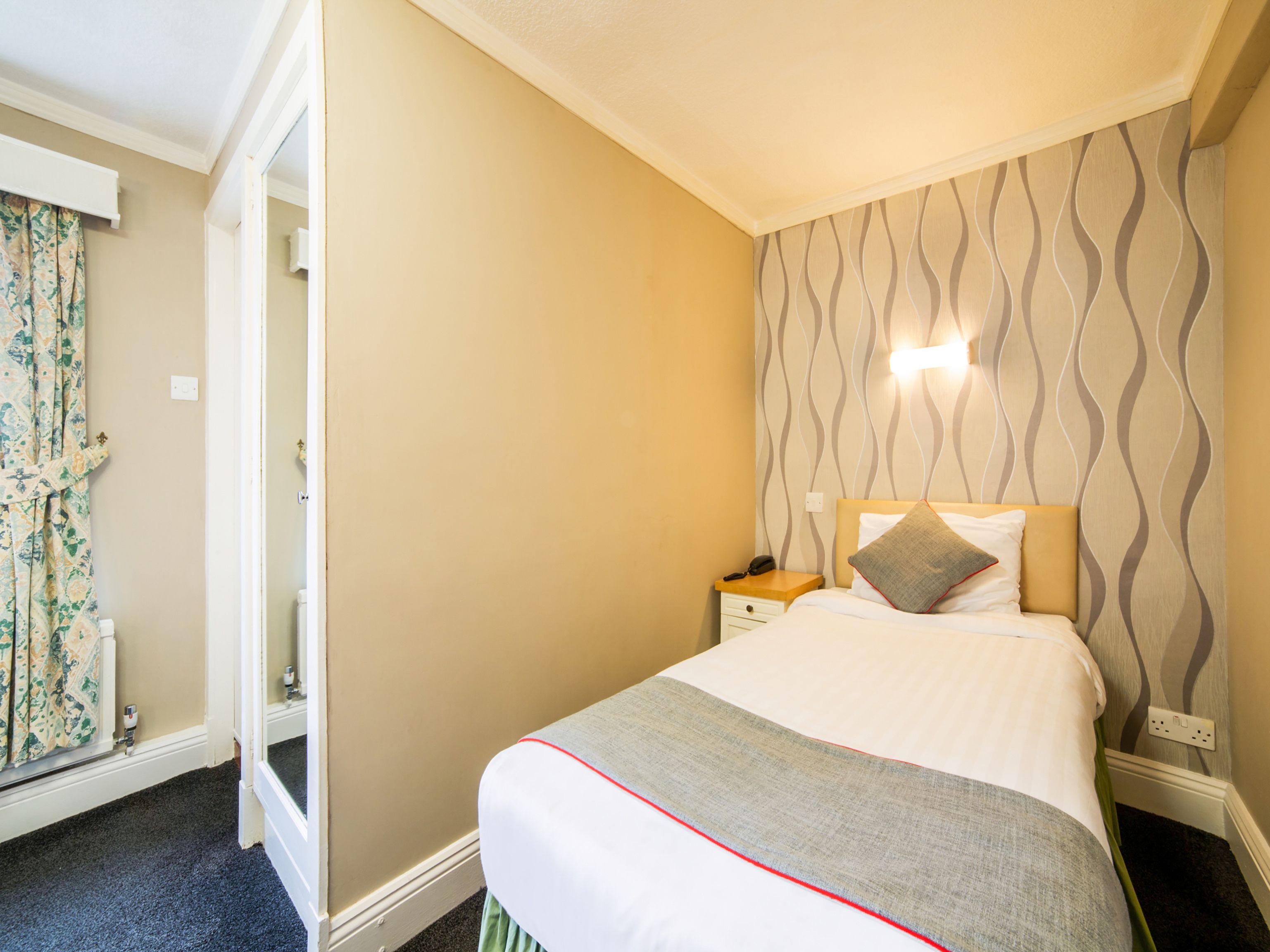 Una habitación de hotel con cama, mesita de noche y pared con diseño.