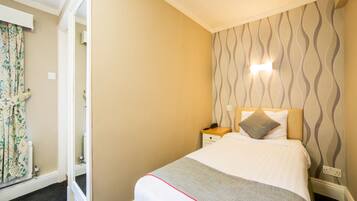 Una habitación de hotel con cama, mesita de noche y pared con diseño.