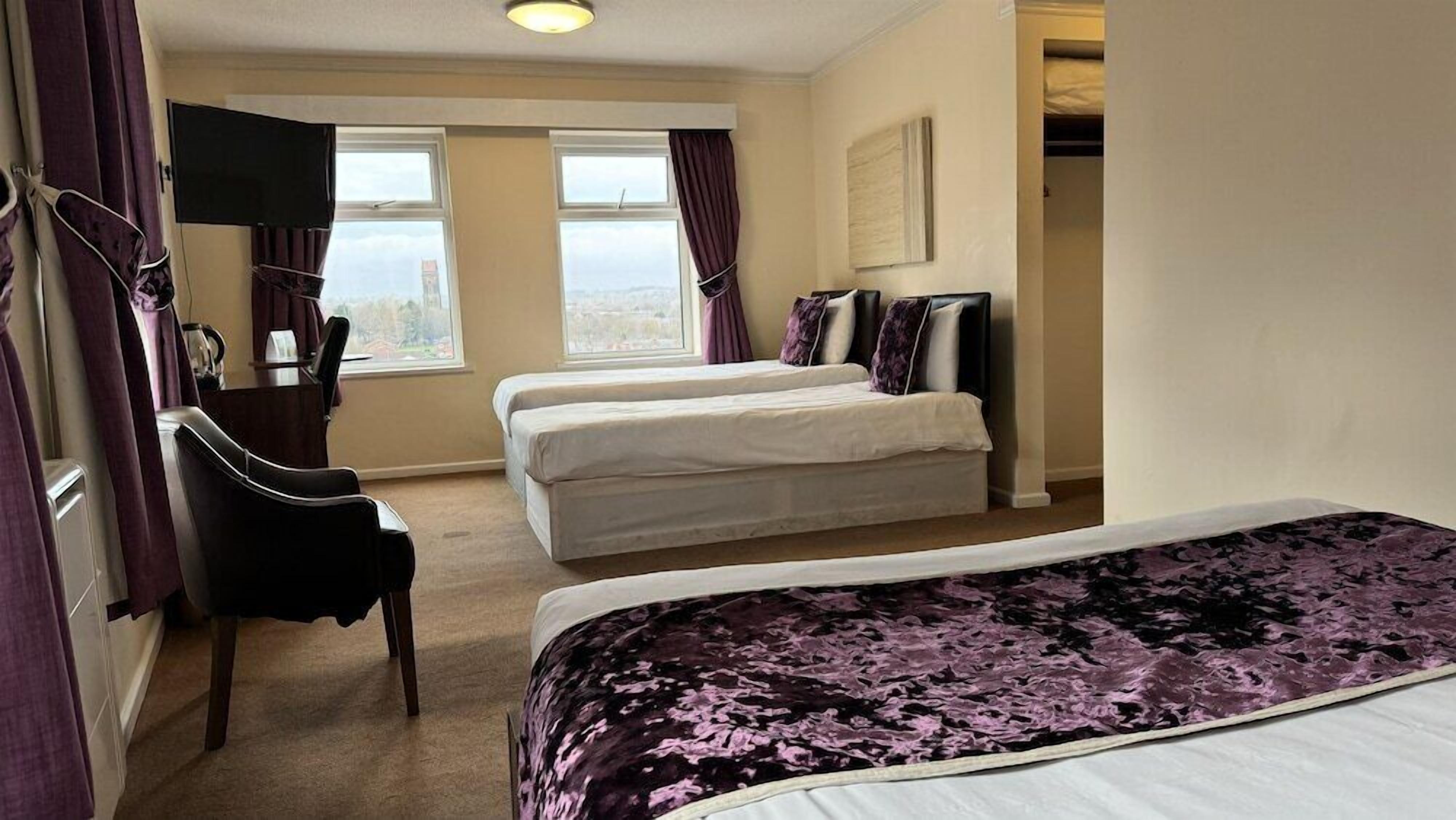 A hotel room with two beds, a TV, a chair, and a window with a view.
