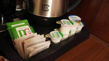 Una encimera de cocina con una cafetera, un montón de toallas de papel y varios envases de leche.