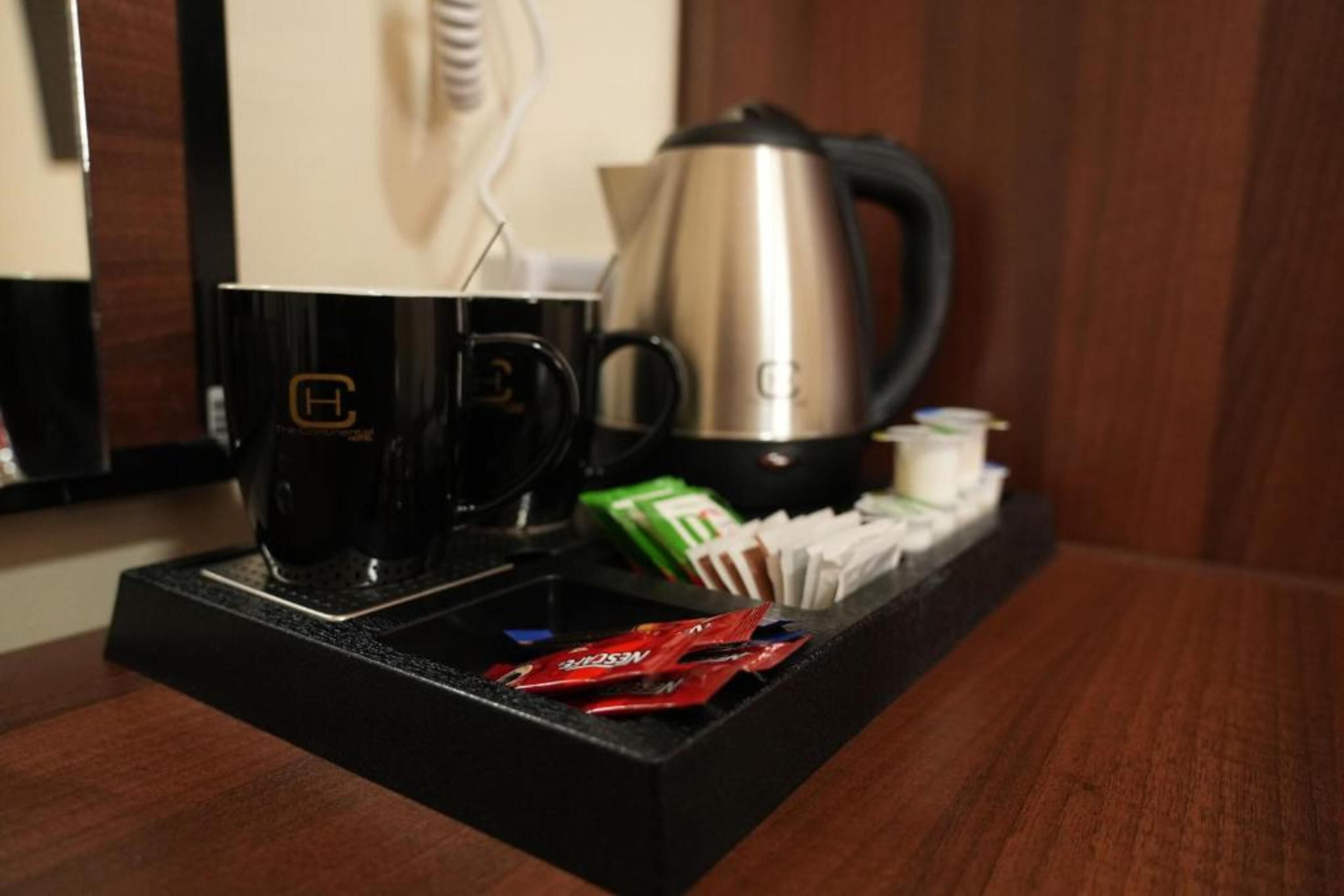 A coffee station with a coffee maker, cups, and packets of coffee creamer.