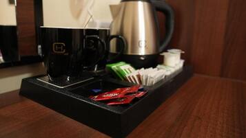 A coffee station with a coffee maker, cups, and packets of coffee creamer.