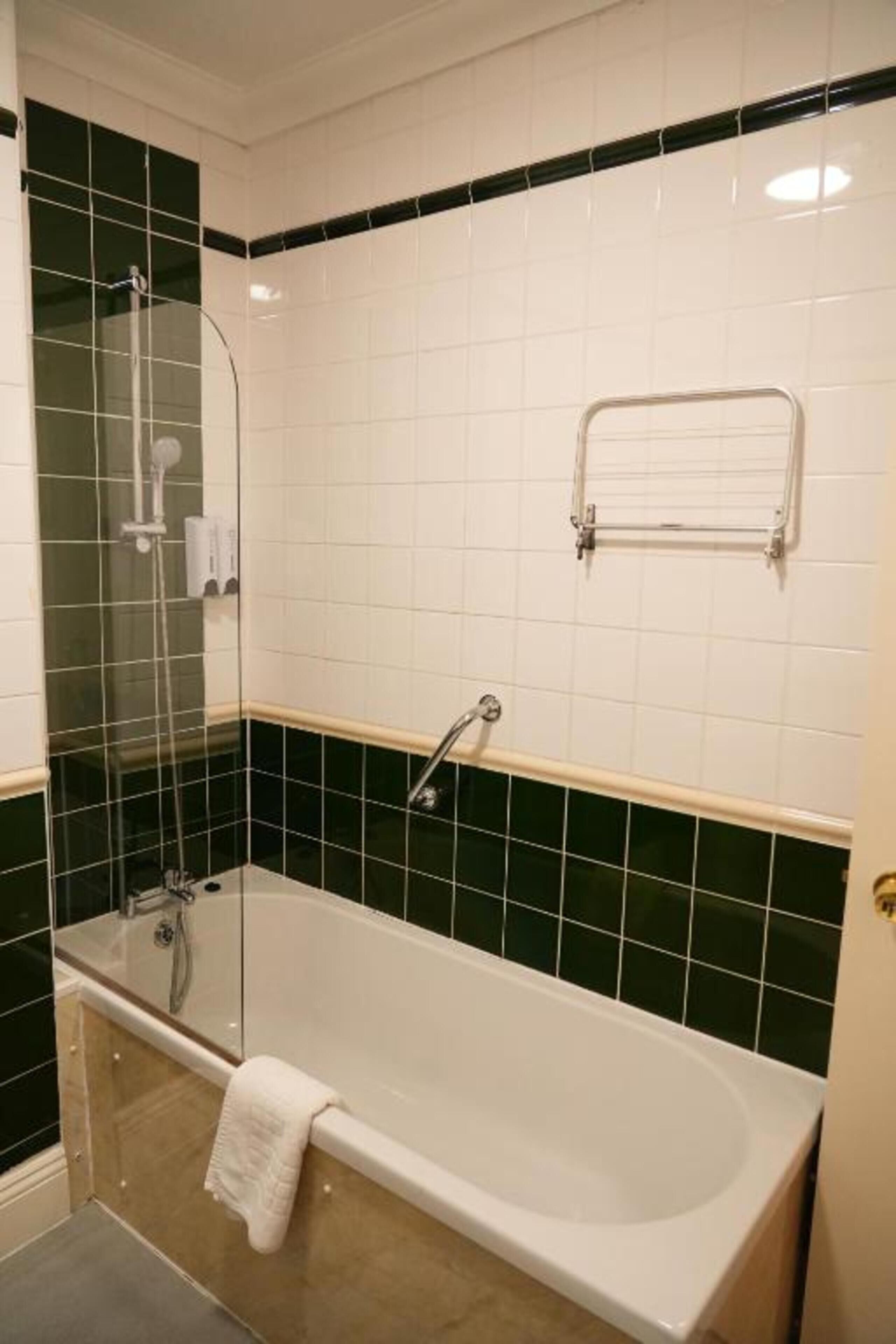 A bathroom with a bathtub, a glass shower enclosure, and a towel rack.