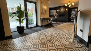 A hotel lobby with patterned flooring, a large potted plant, a reception desk, and a staircase. - The Continental Hotel, Derby (Derby)
