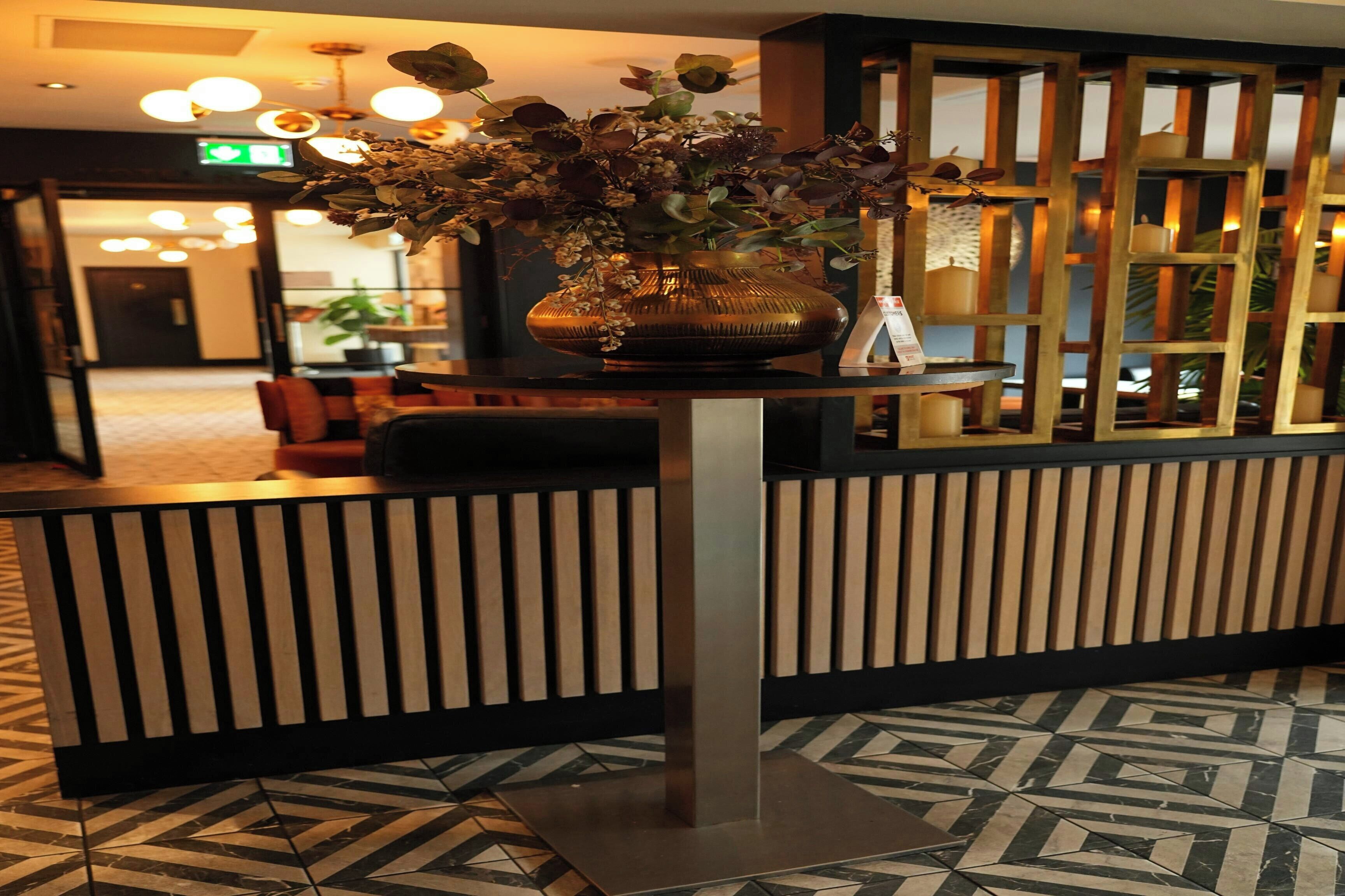 A reception area with a decorative vase, a patterned floor, and a modern reception desk.