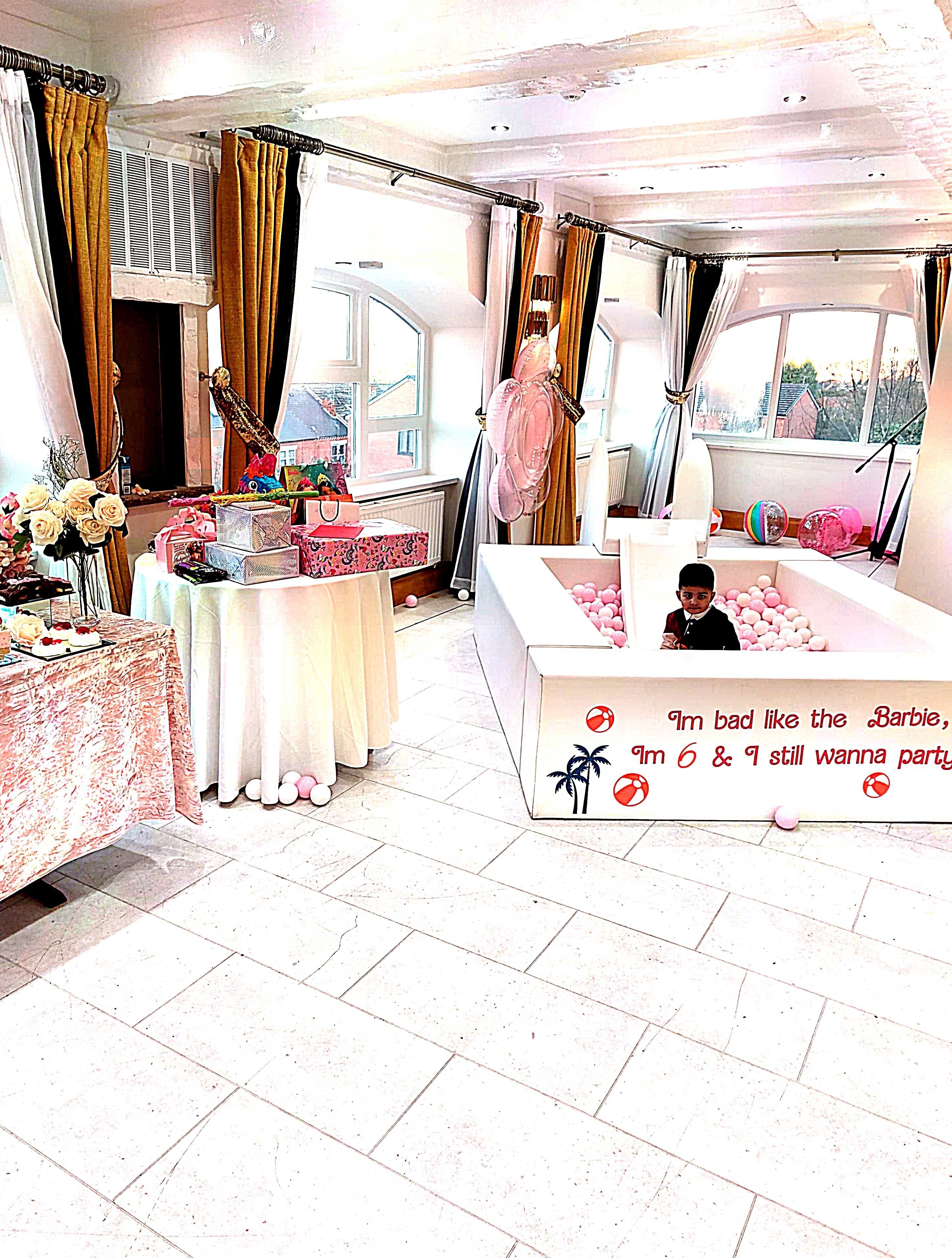 Een kamer met een pooltafel, een tafel met cadeaus en een tafelvoetbaltafel met roze ballen.