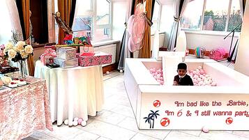Een kamer met een pooltafel, een tafel met cadeaus en een tafelvoetbaltafel met roze ballen.