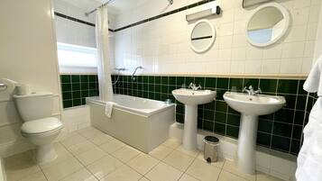 A bathroom with a bathtub, two sinks, a toilet, and a shower curtain.