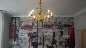 A dining area with a mural depicting London landmarks, a chandelier, and a table set for dining. - Chelsea House Hotel (London)
