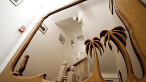 A wooden mirror with a unique design, reflecting a staircase and a wall with framed pictures. - The Rosscourt - Adults only (Bournemouth)