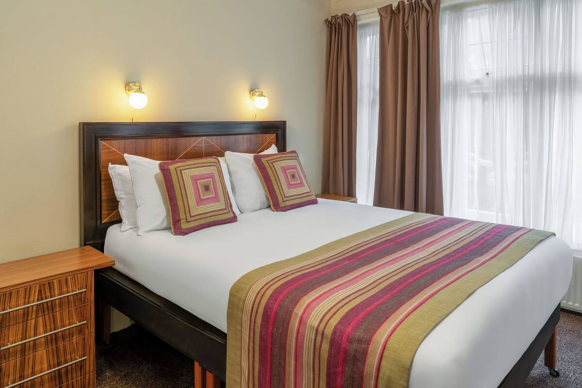 A neatly made bed with a striped blanket, two pillows, and a wooden headboard.