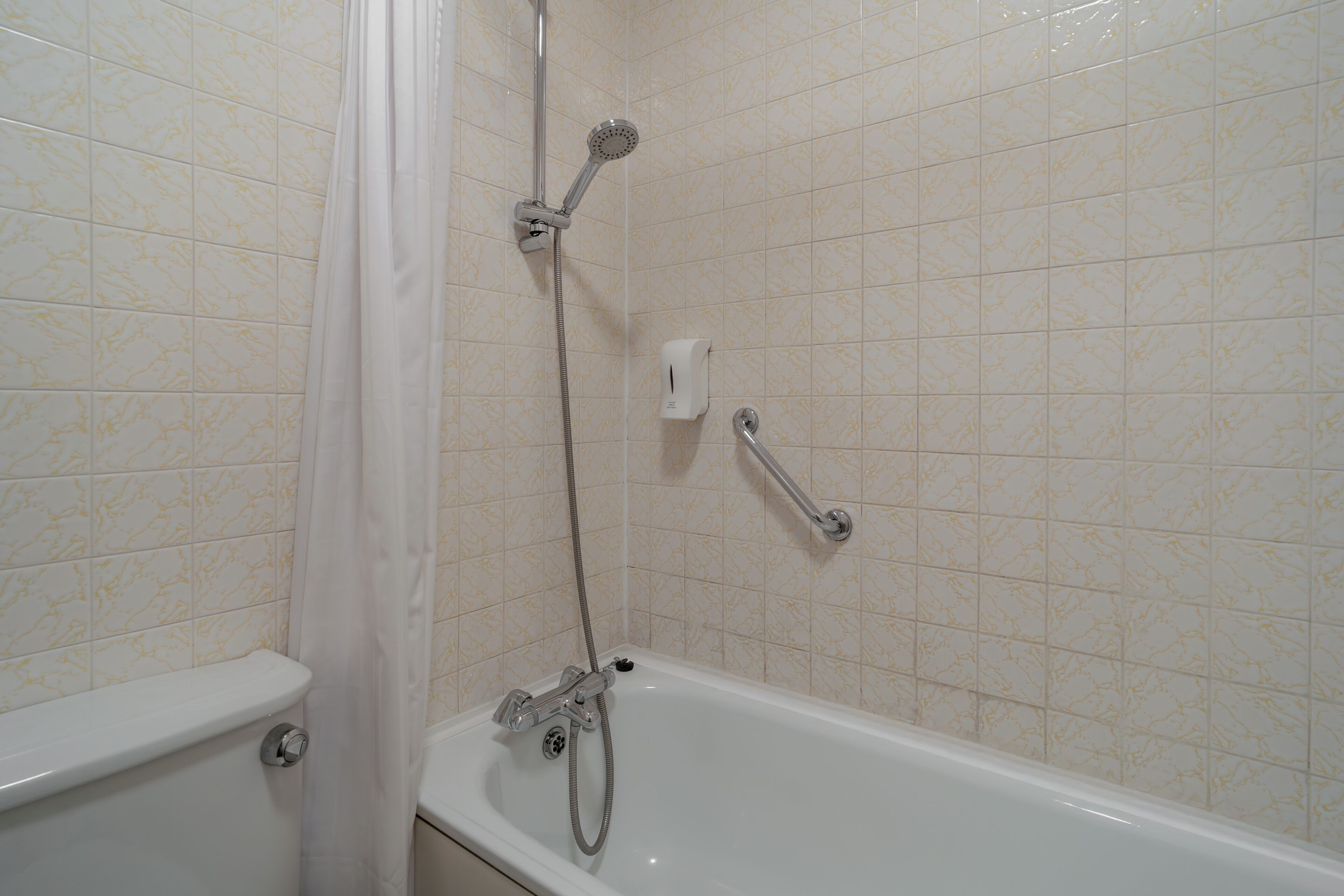 A bathroom with a bathtub, shower, and toilet.