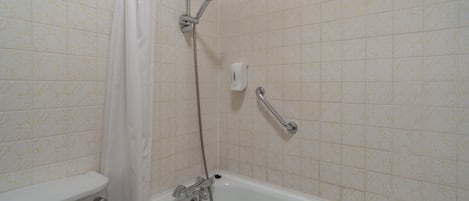 A bathroom with a bathtub, shower, and toilet.