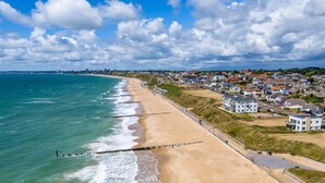 Una cittadina costiera con spiaggia sabbiosa, un lungomare e edifici residenziali.