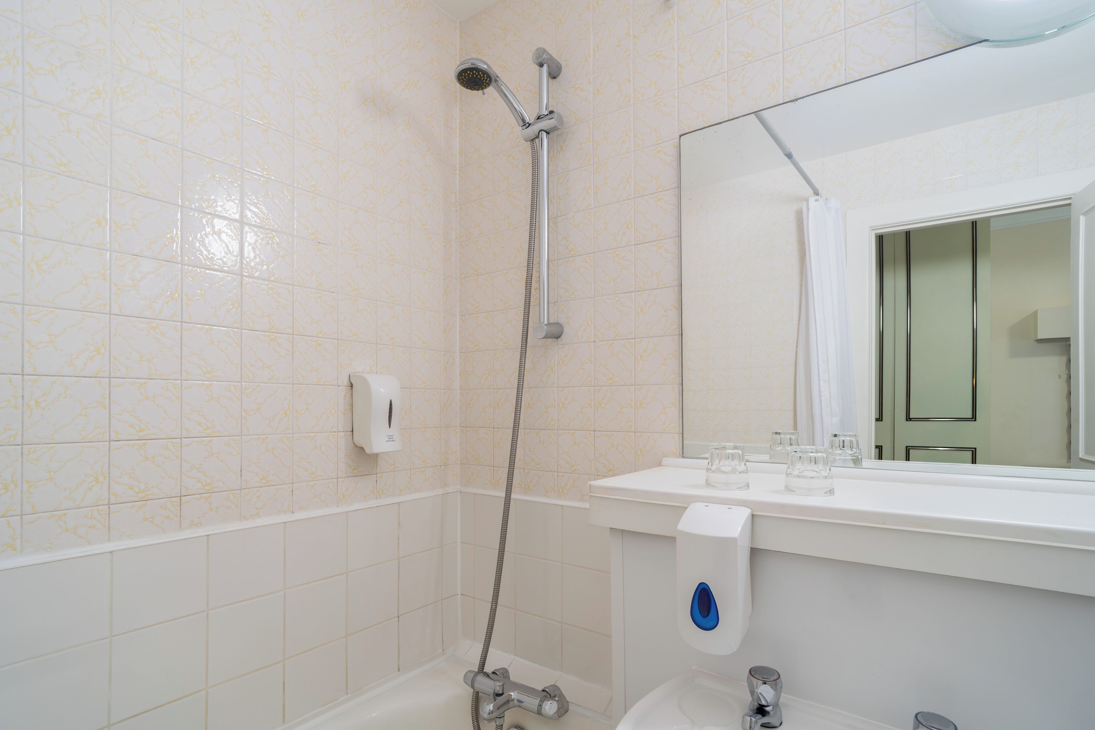 Une salle de bain équipée d’une douche, de toilettes, d’un lavabo et d’un miroir.