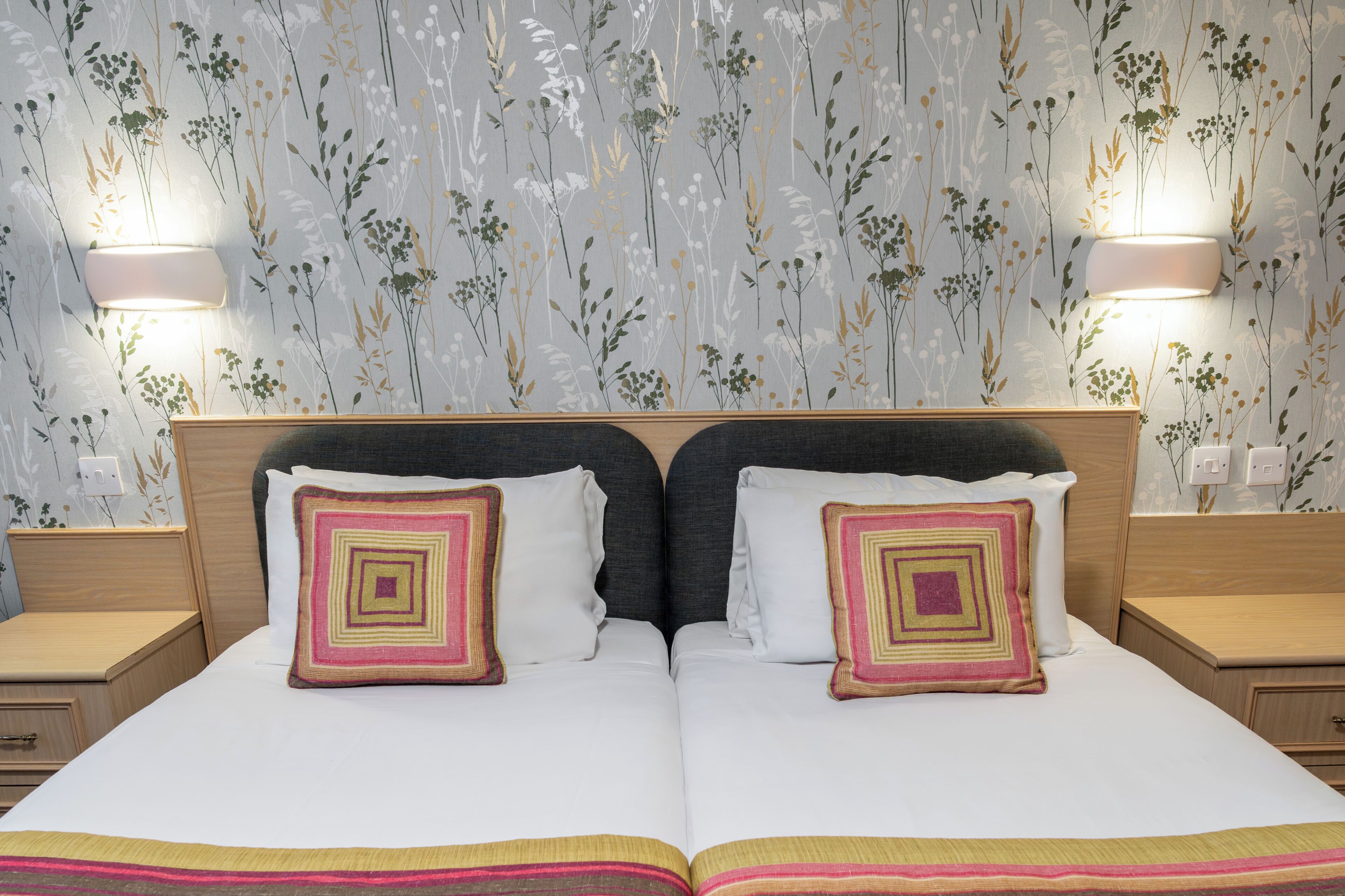 A double bed with two pillows, a headboard, and two bedside tables with lamps.