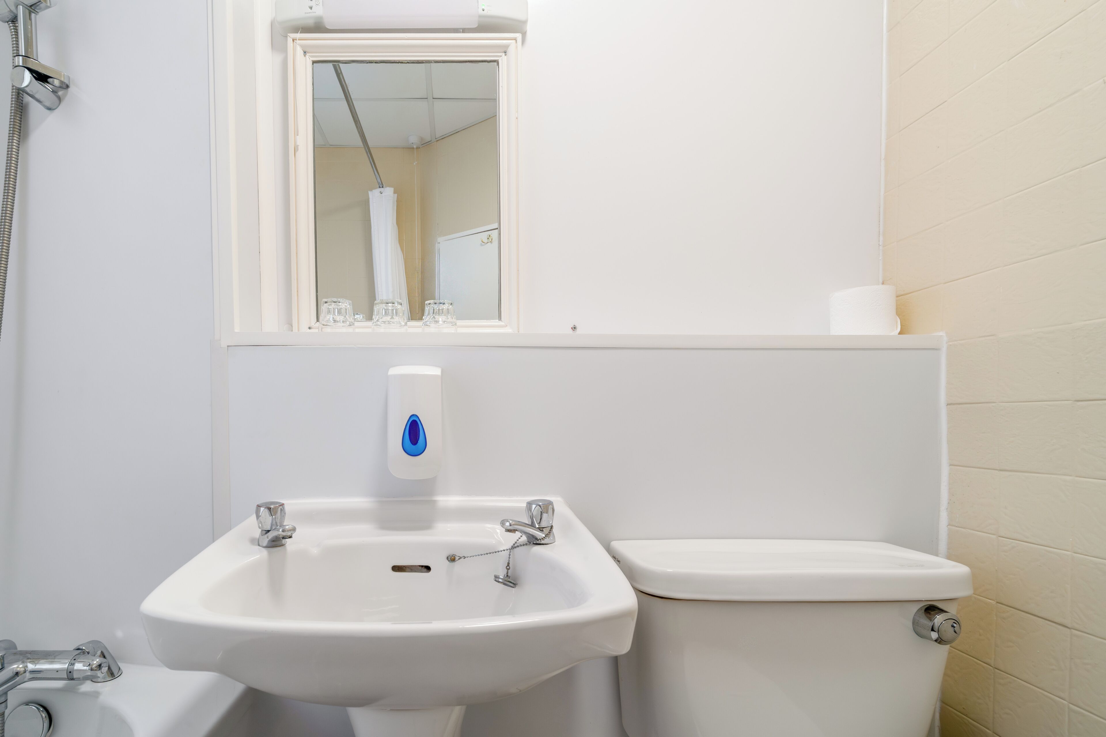 A bathroom with a white sink, a toilet, and a mirror above the sink.