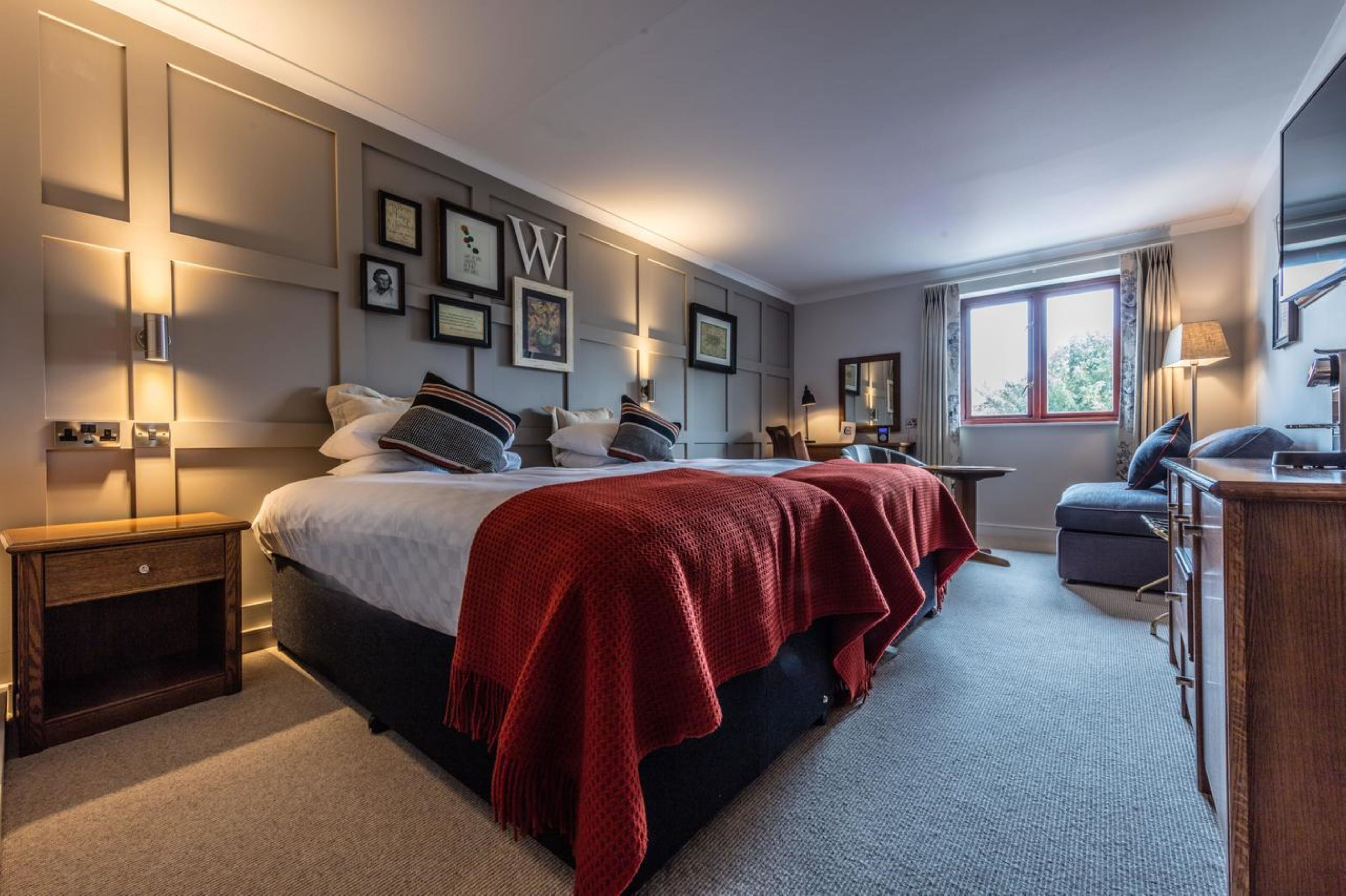 A modern hotel room with a large bed, bedside tables, a desk, and a window with curtains.