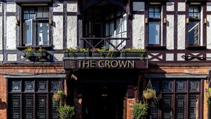 Il s’agit d’un bâtiment traditionnel sur lequel on peut lire l’inscription « The Crown ». Il se distingue par sa façade en bois sombre, ses nombreuses fenêtres ornées de grilles décoratives et les jardinières suspendues qui l’agrémentent.