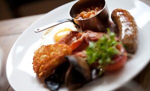 A plate of breakfast food including eggs, bacon, mushrooms, and beans. - Crown Hotel (Chertsey)