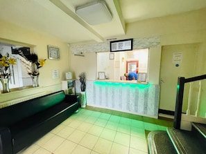 A reception area with a reception desk, a clock, and a sign indicating 'ONE STAFF ALLOWED IN RECEPTION'. - Star Hotel, South Leicester (Leicester)