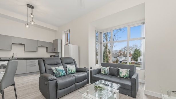 A modern living room with a sofa, a glass coffee table, and a view of the outside.