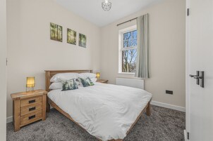 Un dormitorio con cama, mesitas de noche, ventana y decoración en la pared.