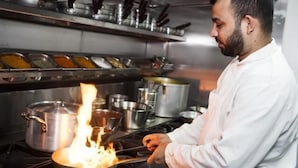 A chef cooking with a pan on a stove.