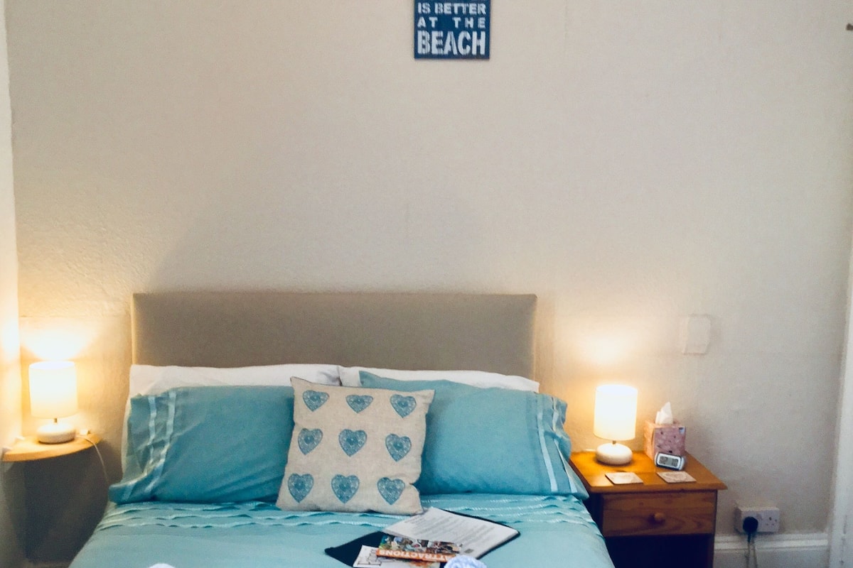 Una cama bien hecha con una decoración azul y blanca, un cartel en la pared que dice