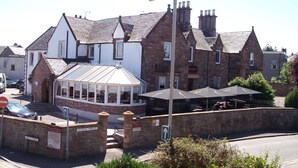 A traditional building with a gabled roof, a covered outdoor seating area, and a sign indicating the name 'Rocklife Hotel'. - The Redcliffe (Inverness)