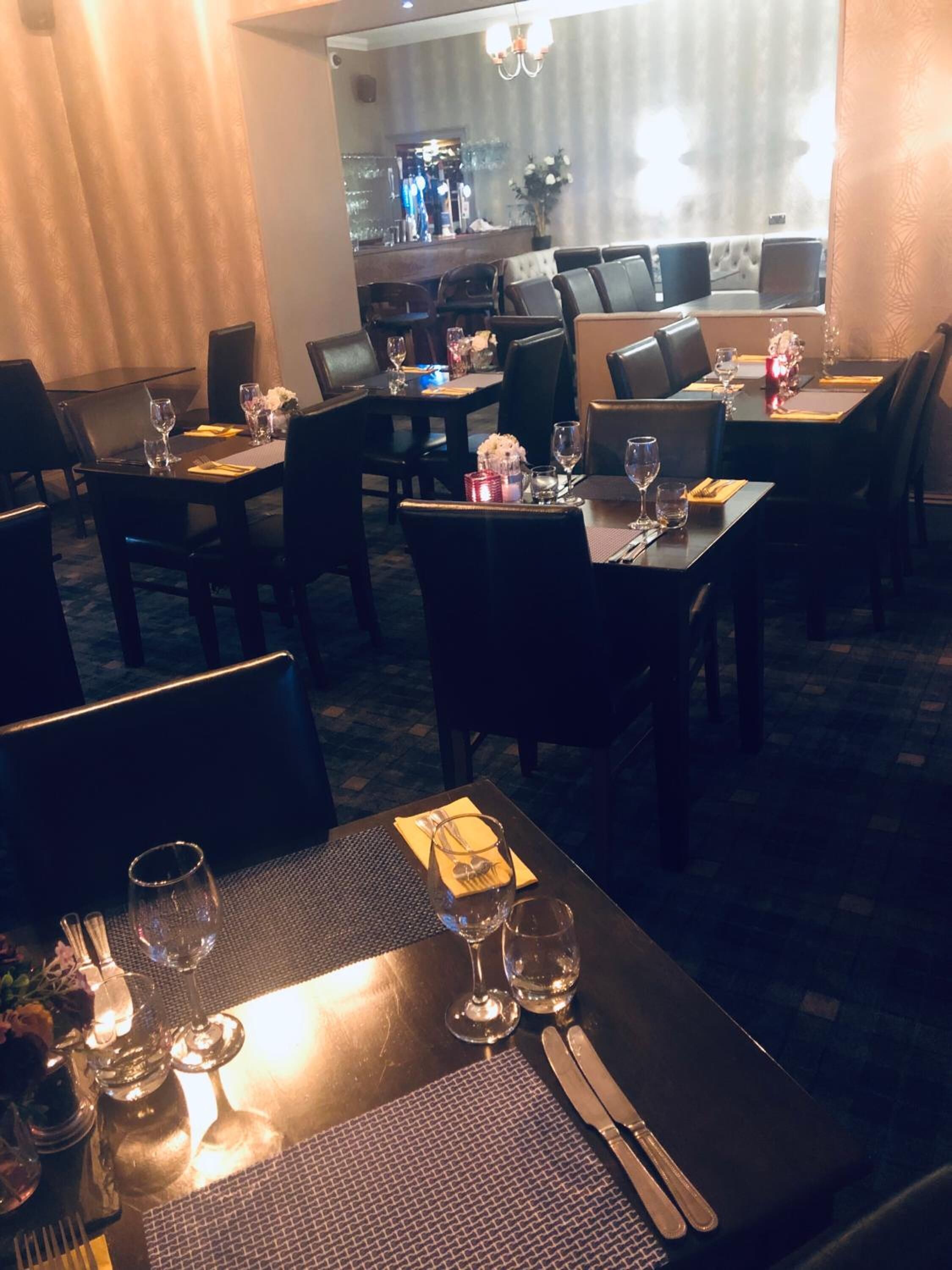 A restaurant with tables set for dining, including cutlery and glasses.