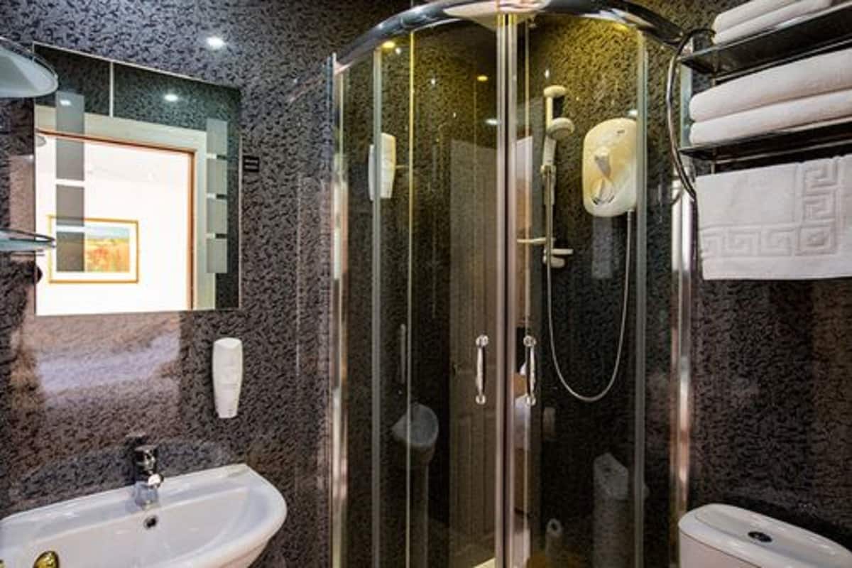 Ett modernt badrum med en dusch som är avskärmad med glasväggar, ett handfat och en toalett.