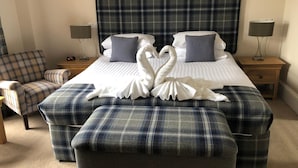 A hotel room with a large bed, two bedside tables, a chair, and a decorative swan towel arrangement. - The Redcliffe (Inverness)